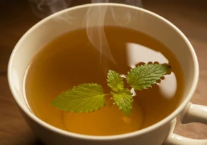 A cup of lemon balm tea with fresh lemon balm leaves, a slice of lemon, and a jar of honey on a rustic wooden table, perfect for weight loss and relaxation.